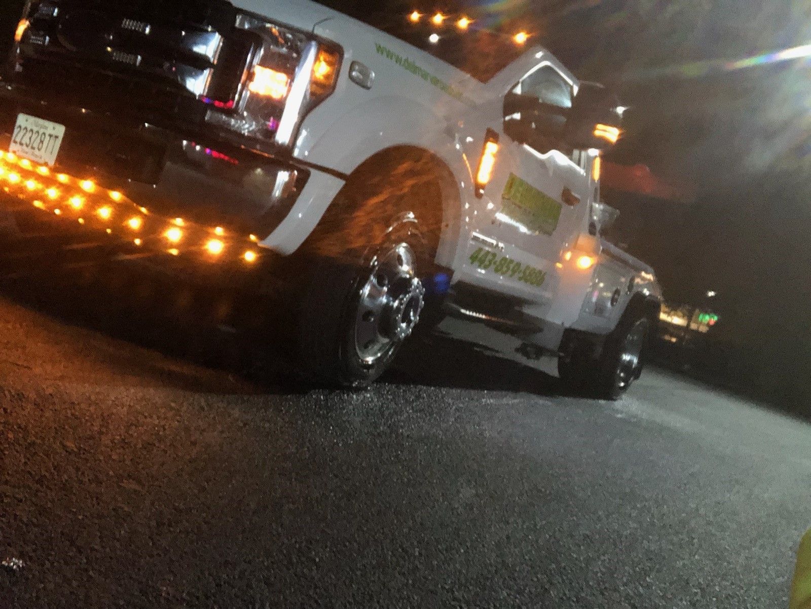 Tow truck with flashing amber lights at night on a dark road