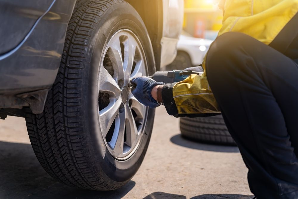 Mechanic tightening a car tire lug nut with a wrench in bright sunlight