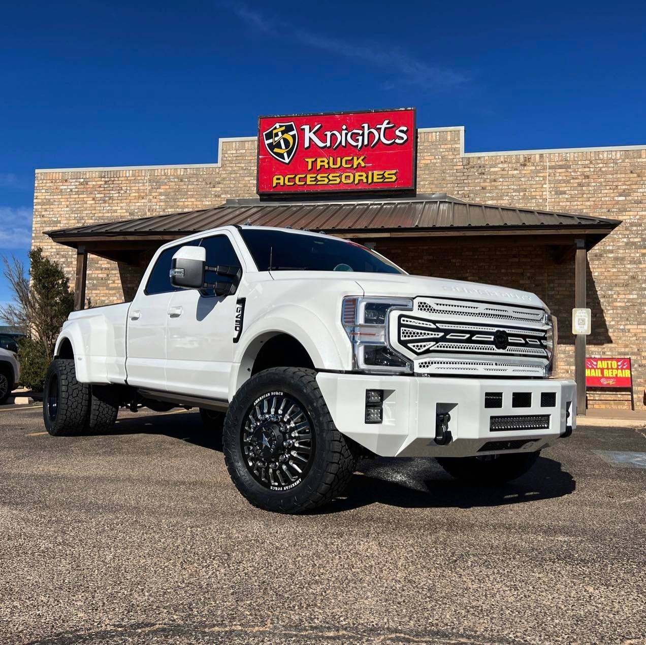 A white truck is parked in front of a truck accessories store.