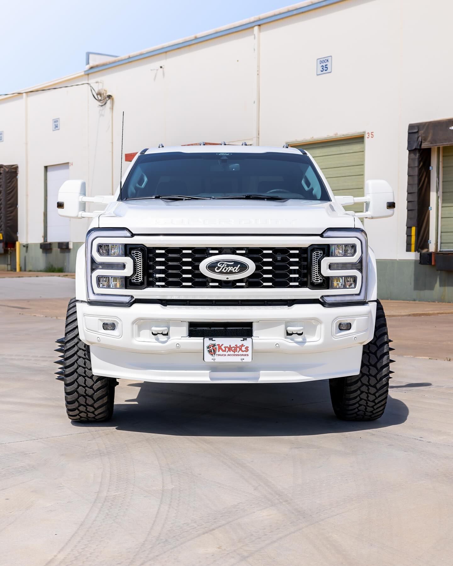 A white ford truck is parked in front of a building.