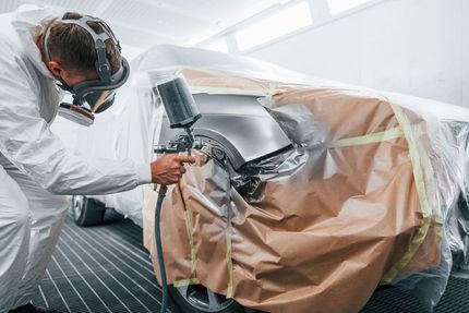 A man is spray painting a car in a garage.