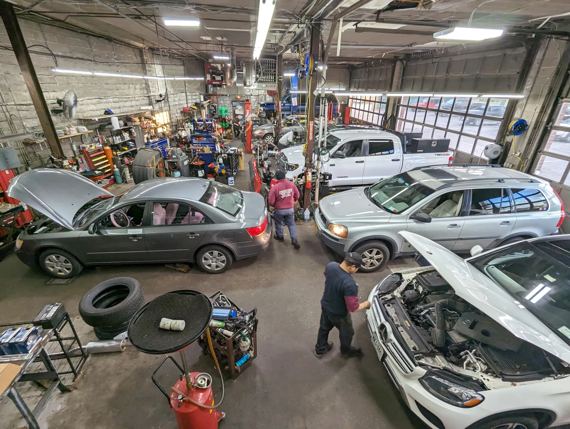 Busy auto repair shop with several cars and mechanics | Dee Pat's Awsomotive