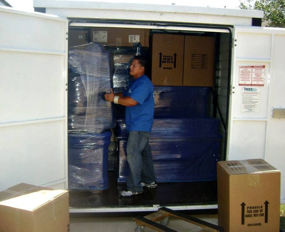Mover loading a truck with wrapped furniture and cardboard boxes
