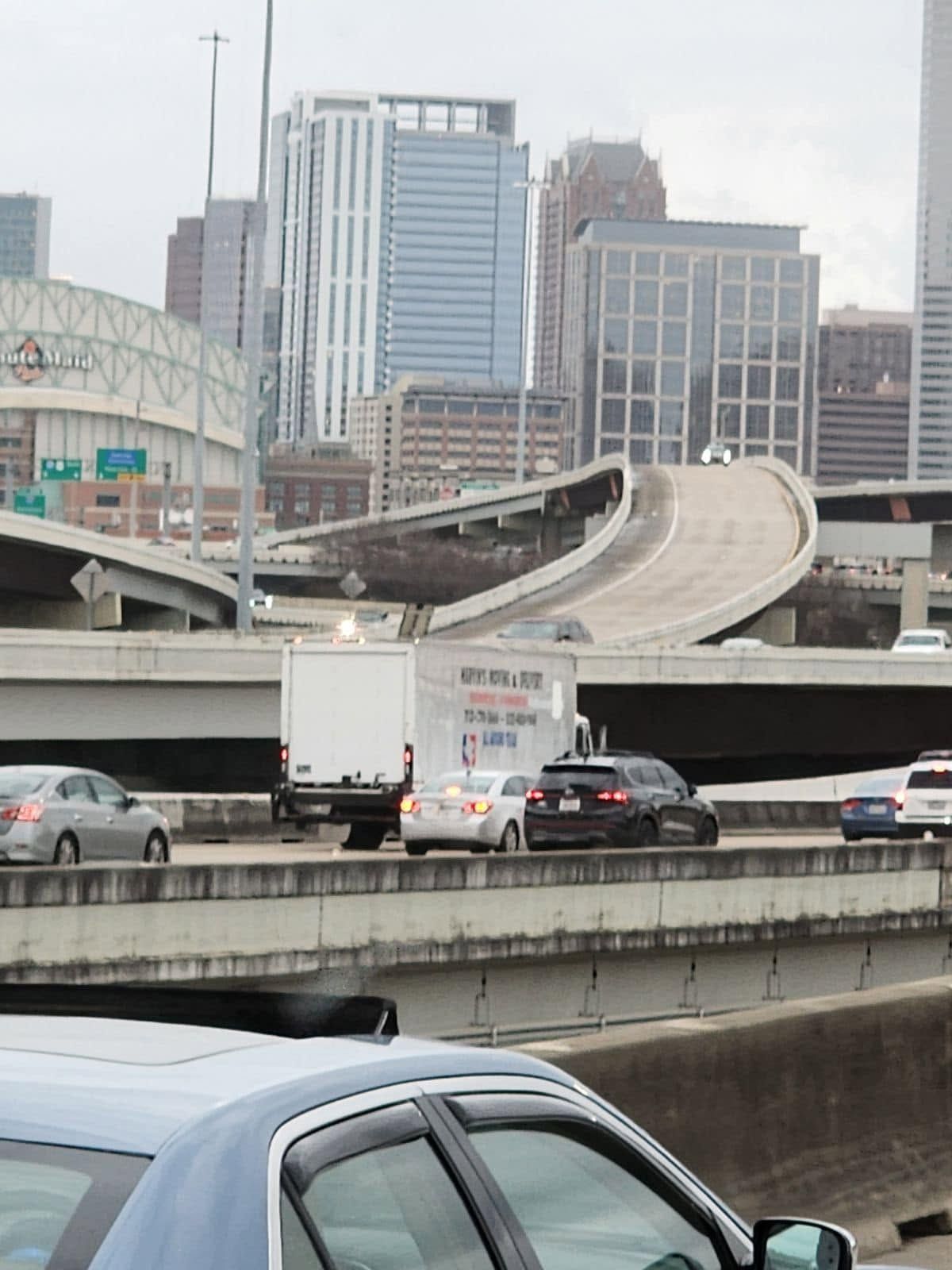 Elevated highway ramp curving over city traffic with downtown buildings in the background