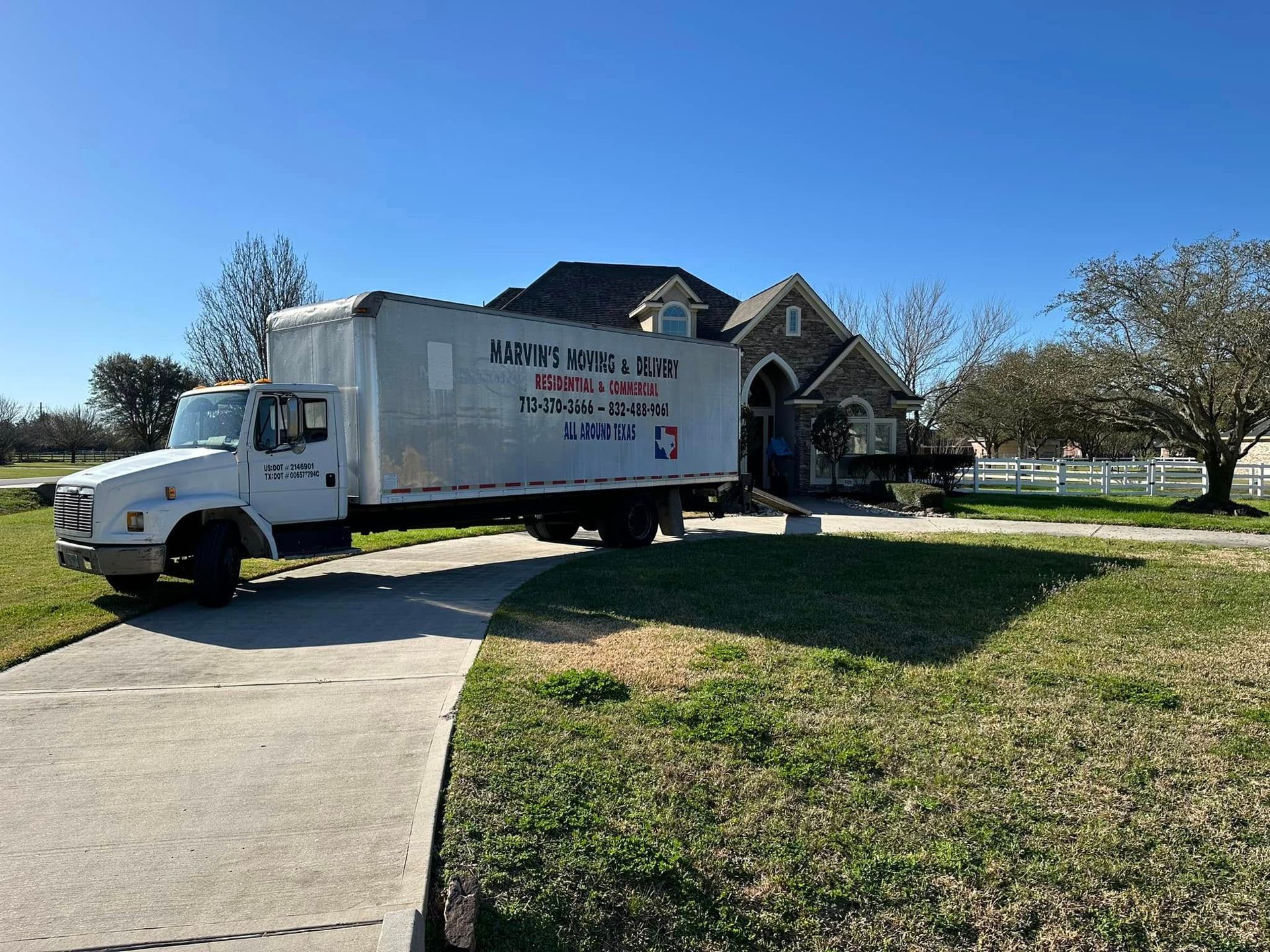 White moving truck parked by a house on a sunny suburban lawn