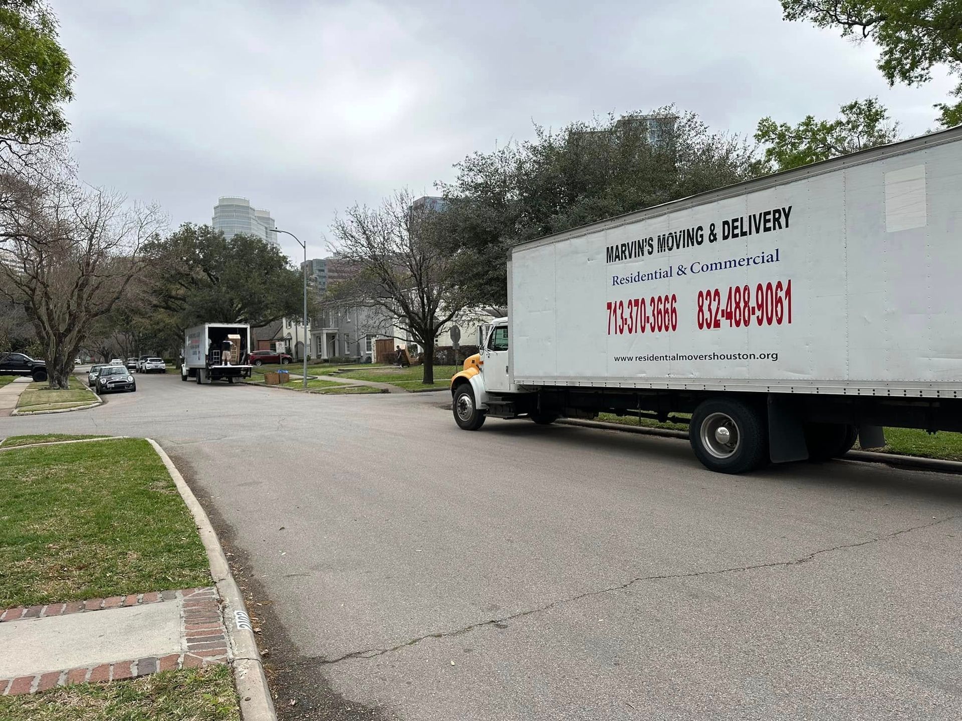 Moving truck parked on a suburban street with trees and overcast sky