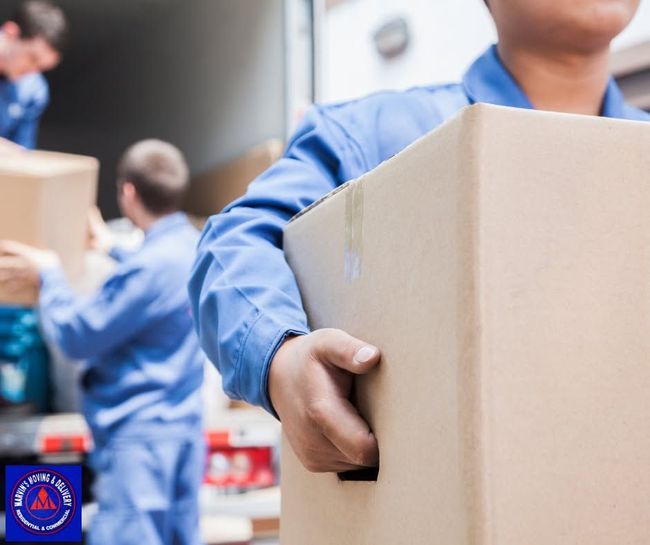 Volunteers in blue uniforms carrying cardboard boxes during a donation drive