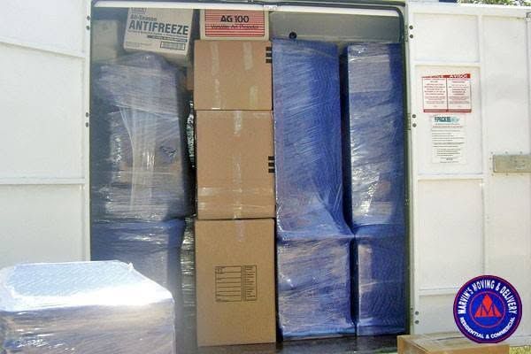 Storage closet packed with cardboard boxes and shrink-wrapped pallets stacked to the ceiling