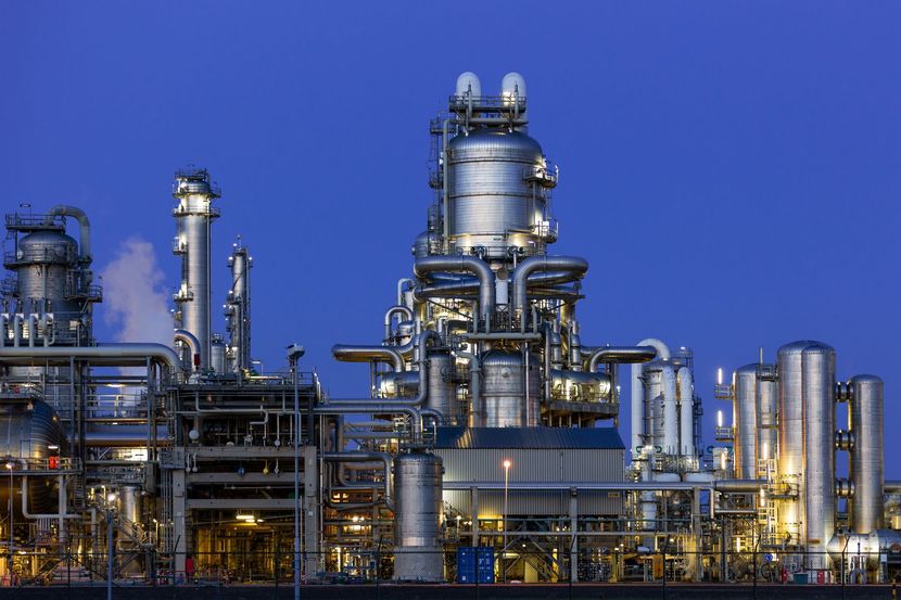 Industrial refinery with silver towers and pipes against a blue sky at dusk