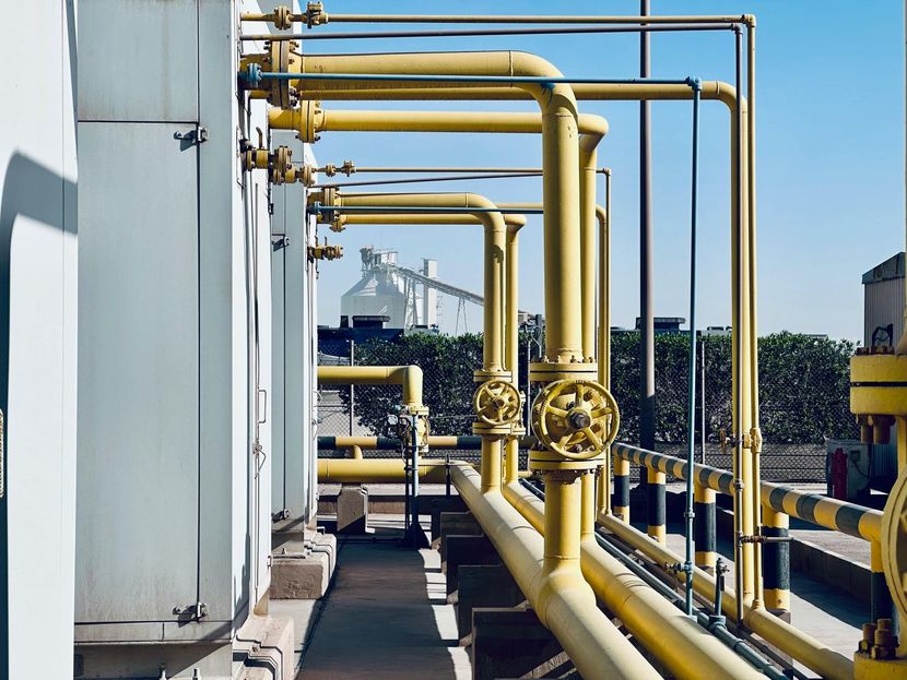 Yellow industrial pipes along a rooftop walkway in a utility plant.