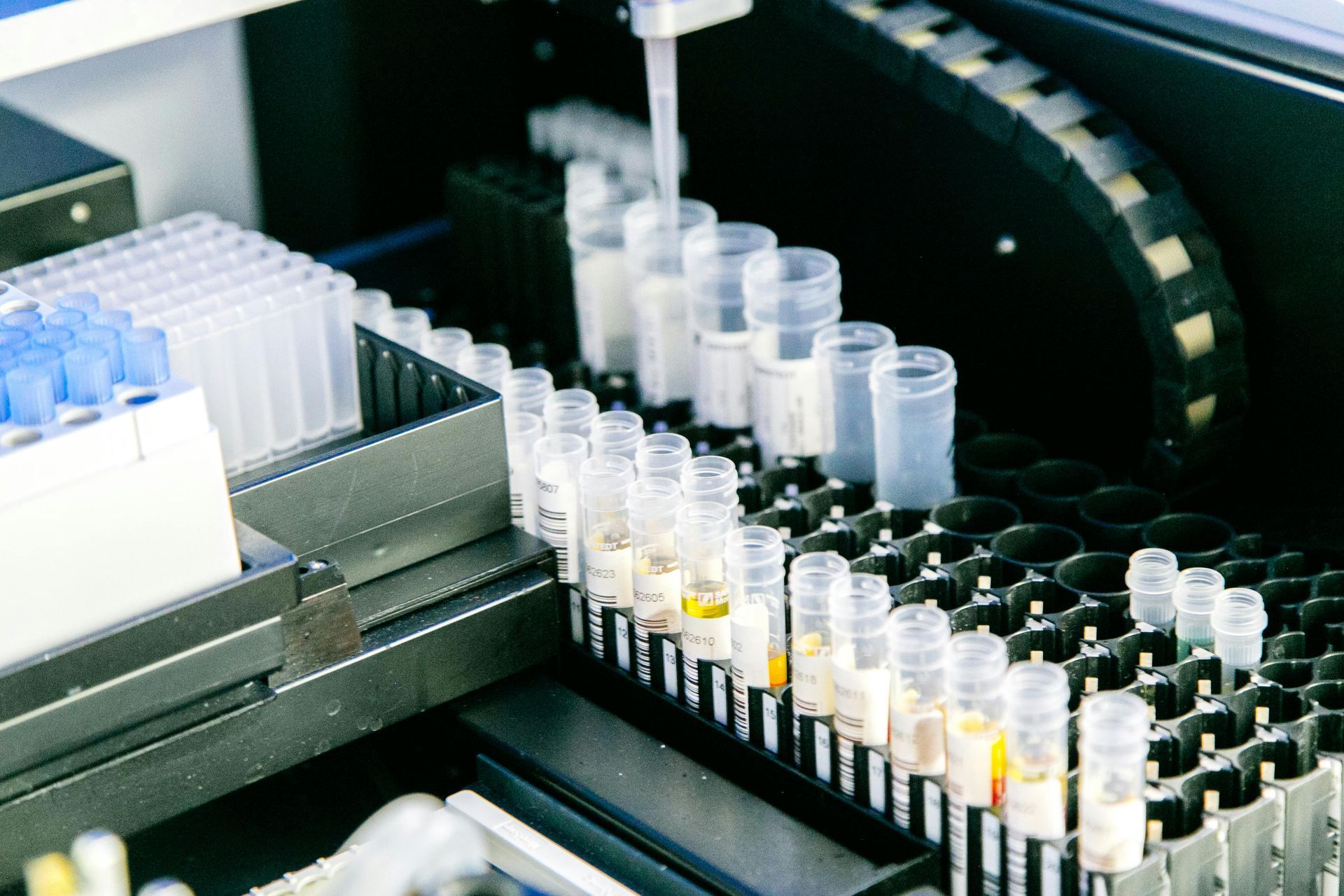 Automated lab machine loading rows of sample vials and tubes on a conveyor