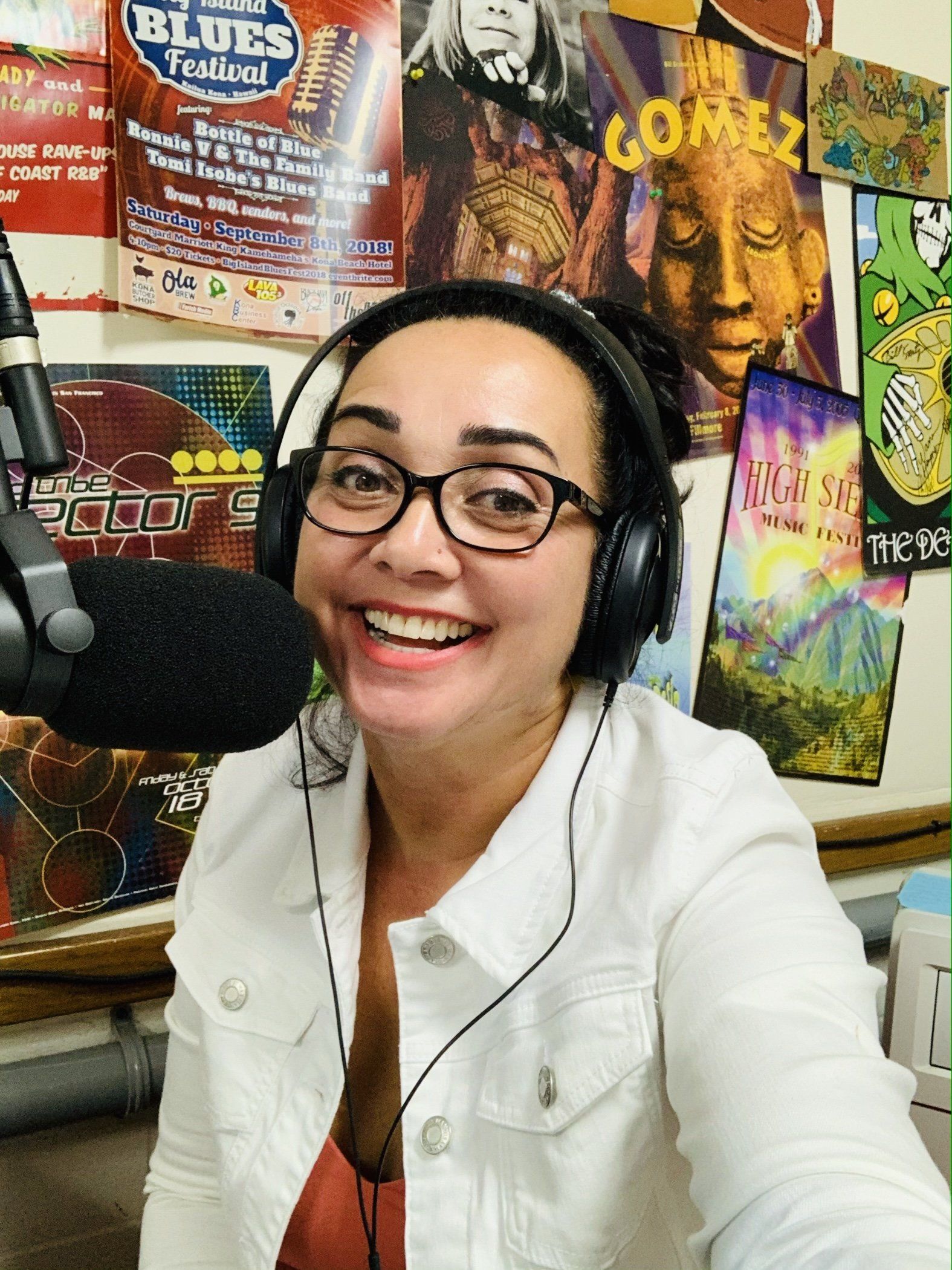 A woman wearing headphones is smiling in front of a microphone.
