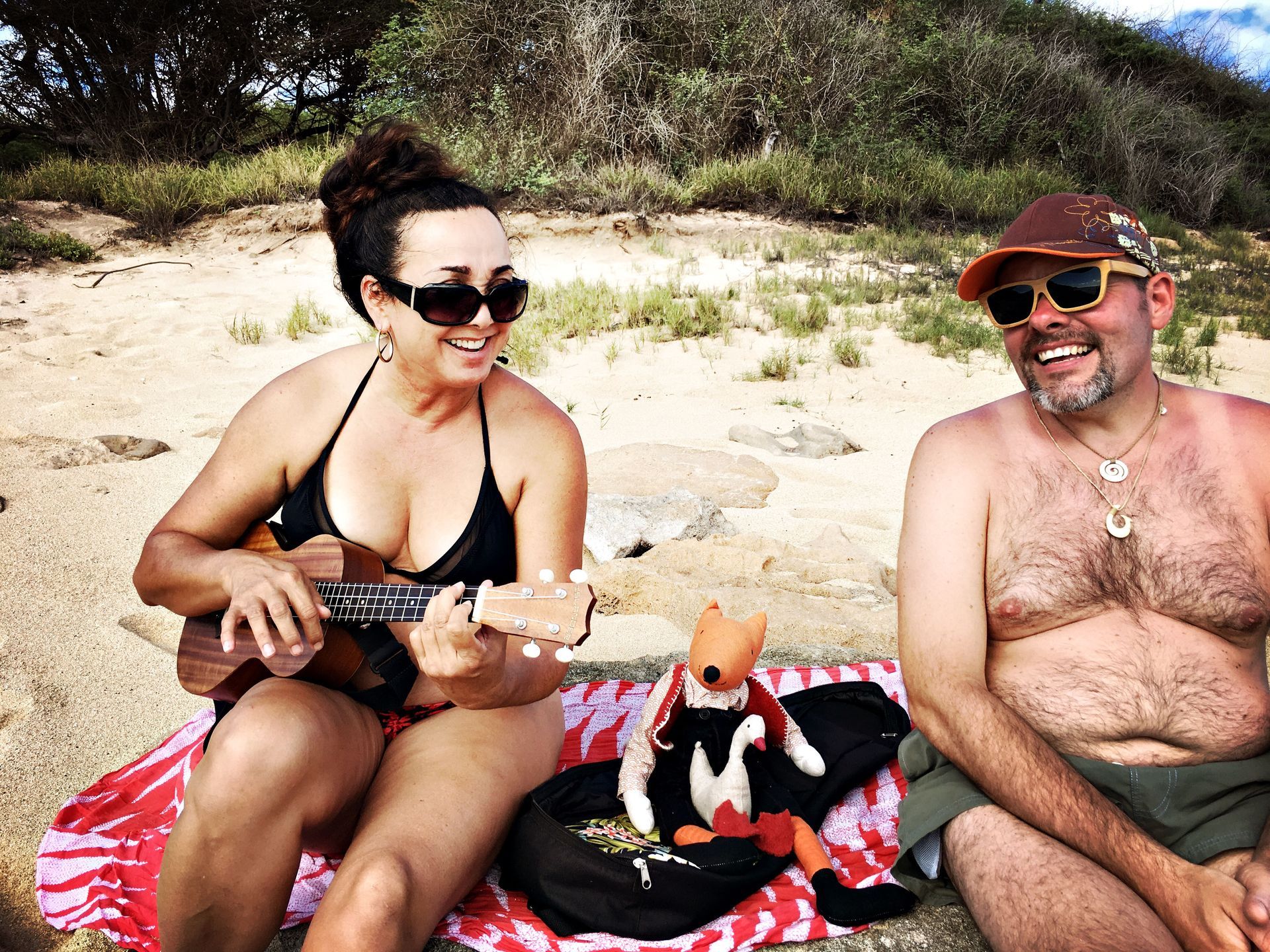 A woman in a bikini is playing an ukulele next to a shirtless man
