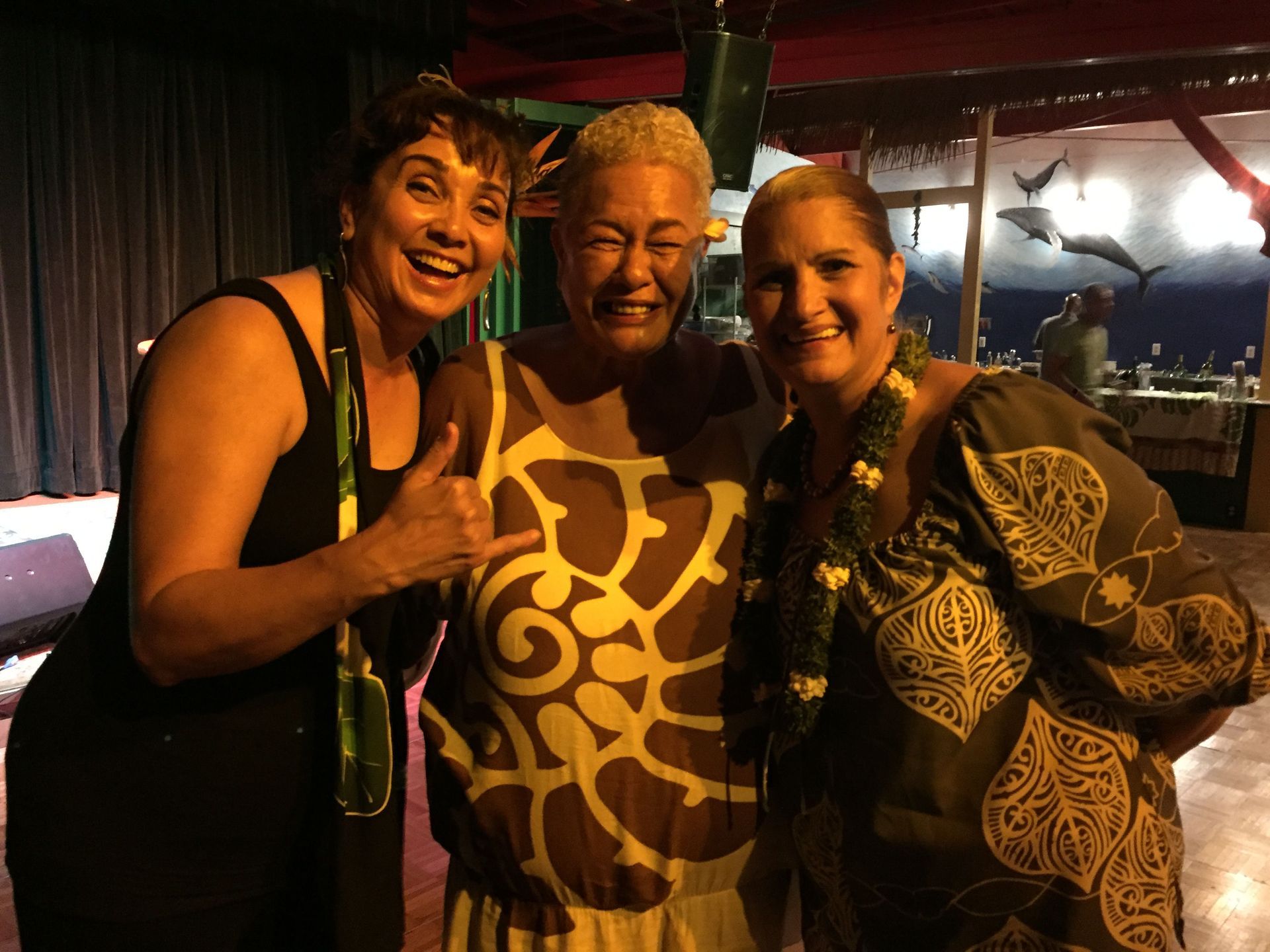 Three women are posing for a picture together and one of them is giving a thumbs up.