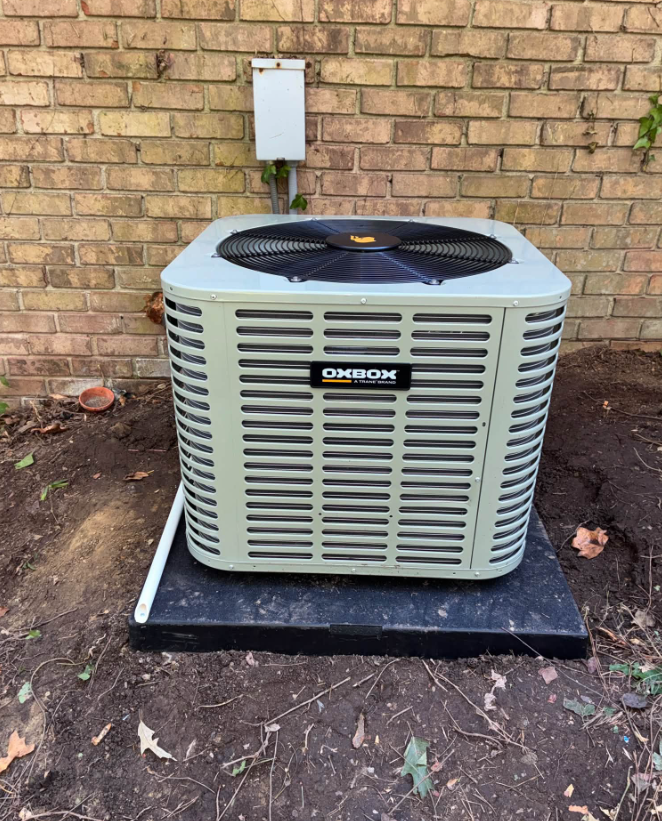 Outdoor HVAC service scene with a gray condenser unit, gauges, and tools on the ground