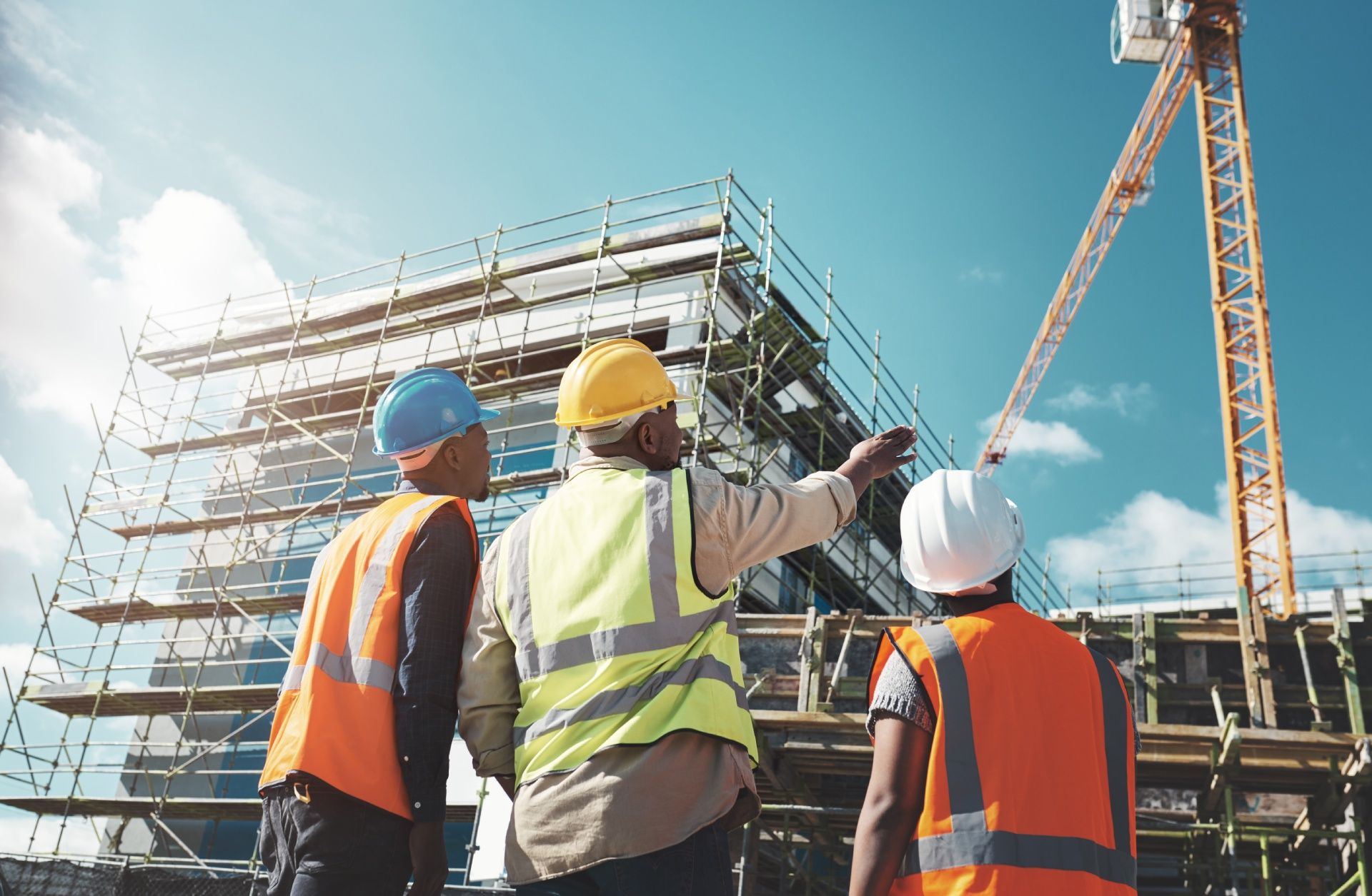 A group of construction workers are standing in front of a building under construction.