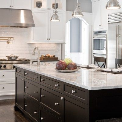 A kitchen with white cabinets and a large island with fruit on it