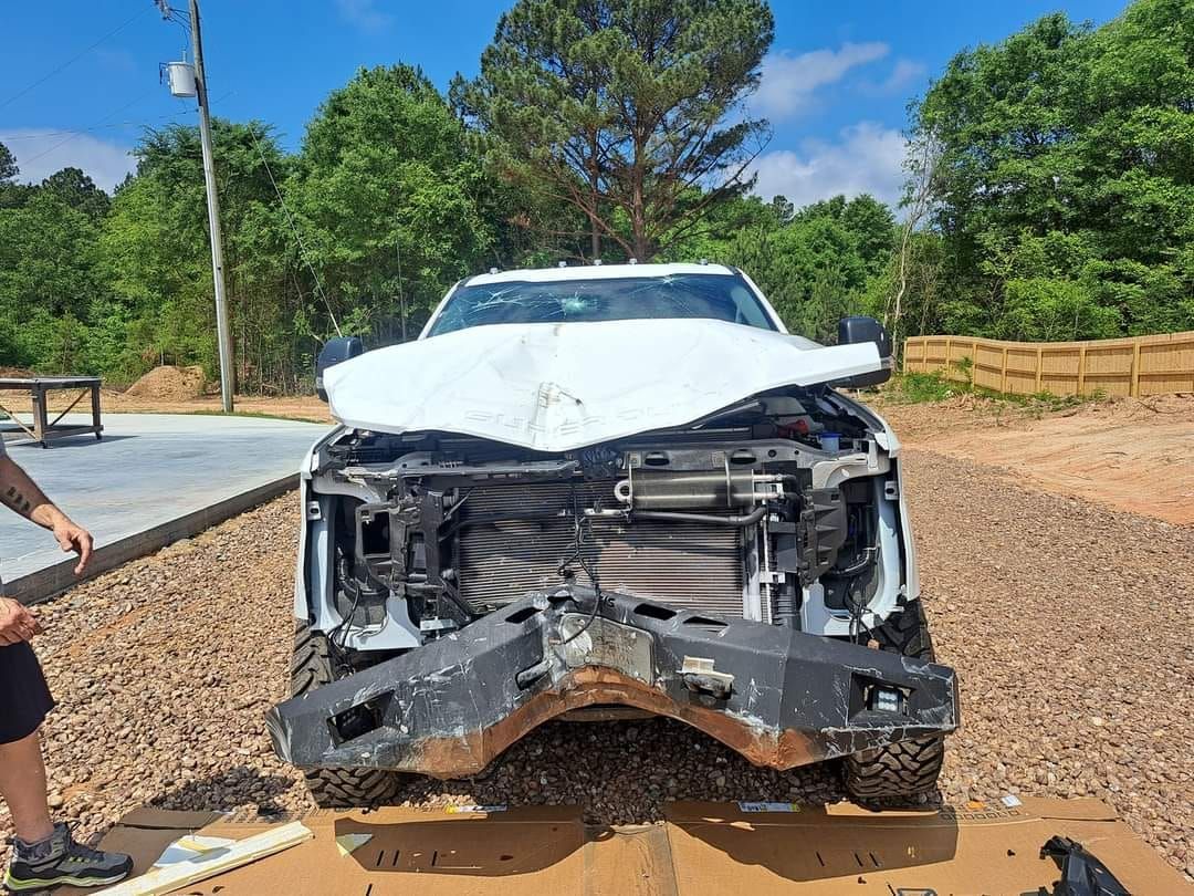 A man is standing next to a wrecked truck.