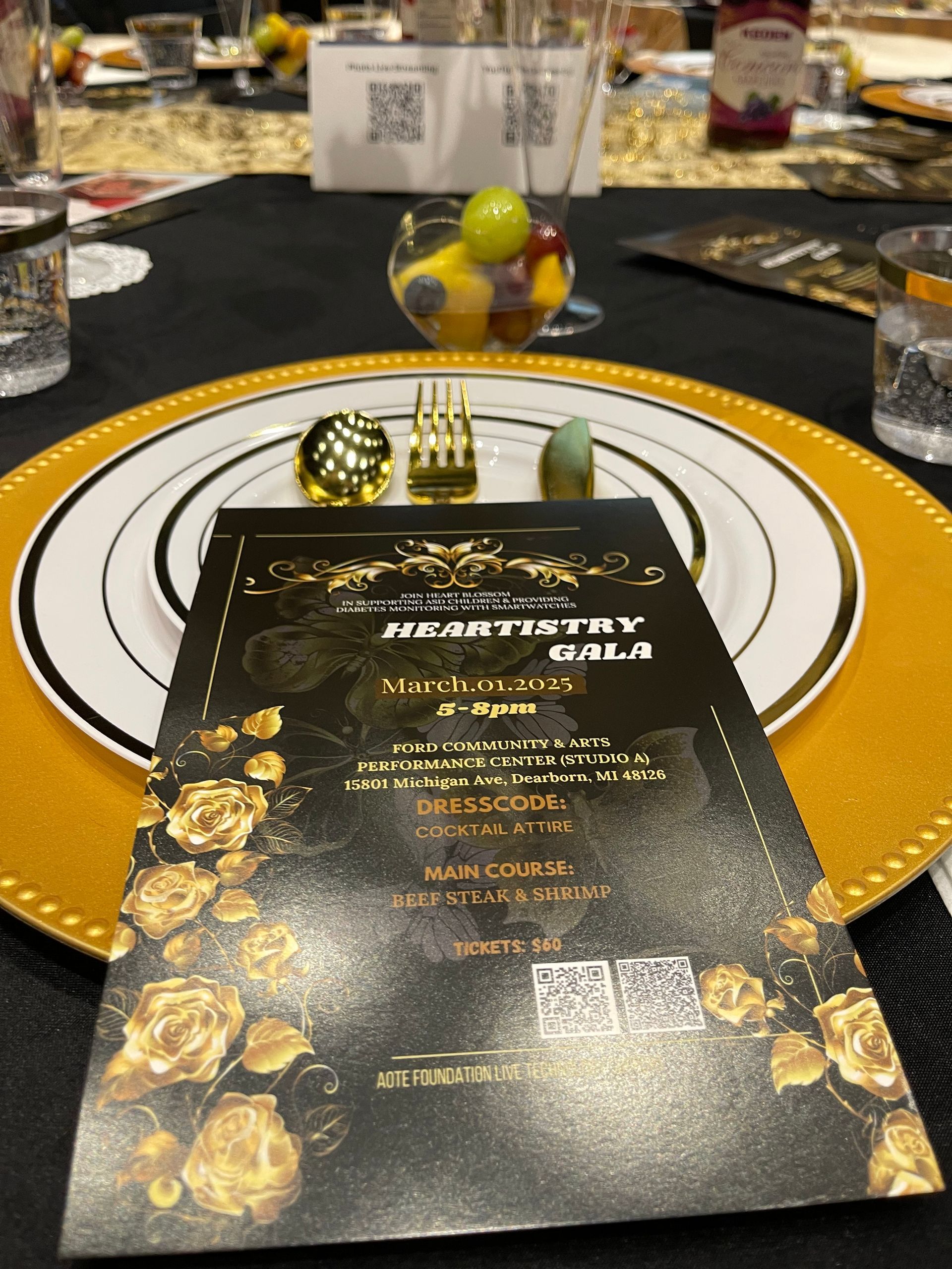 Formal dinner setting: plate with menu, golden decor, fruit in glass.