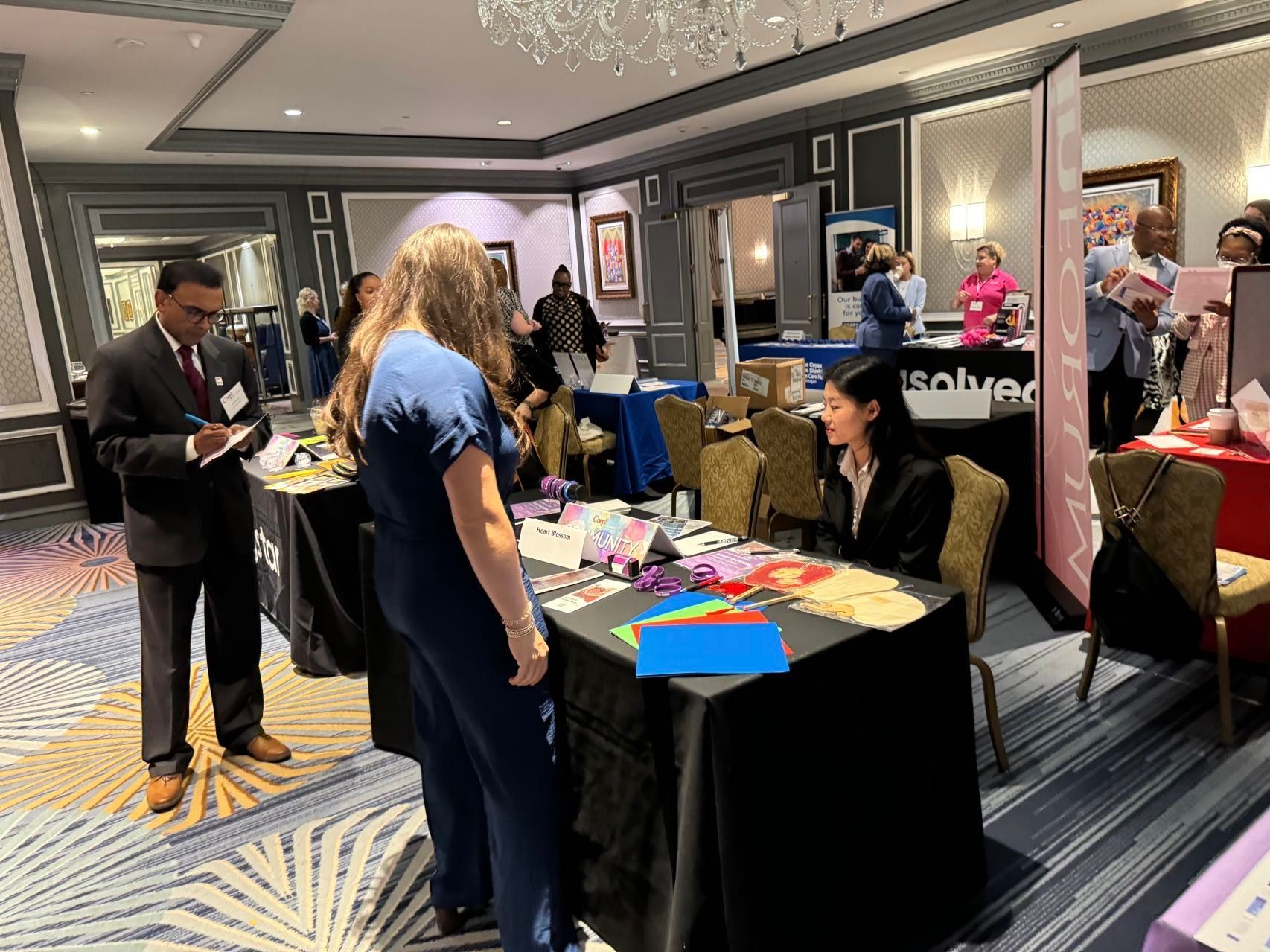 Conference attendees at booths, exchanging information.