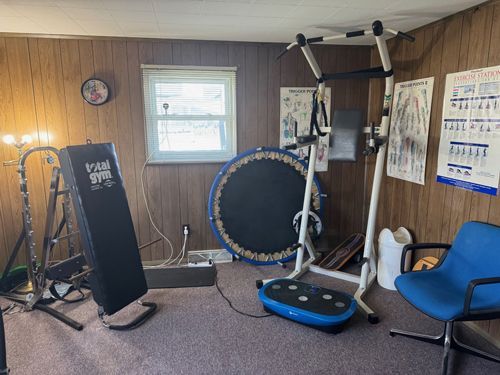 A room with a lot of exercise equipment and a chair.