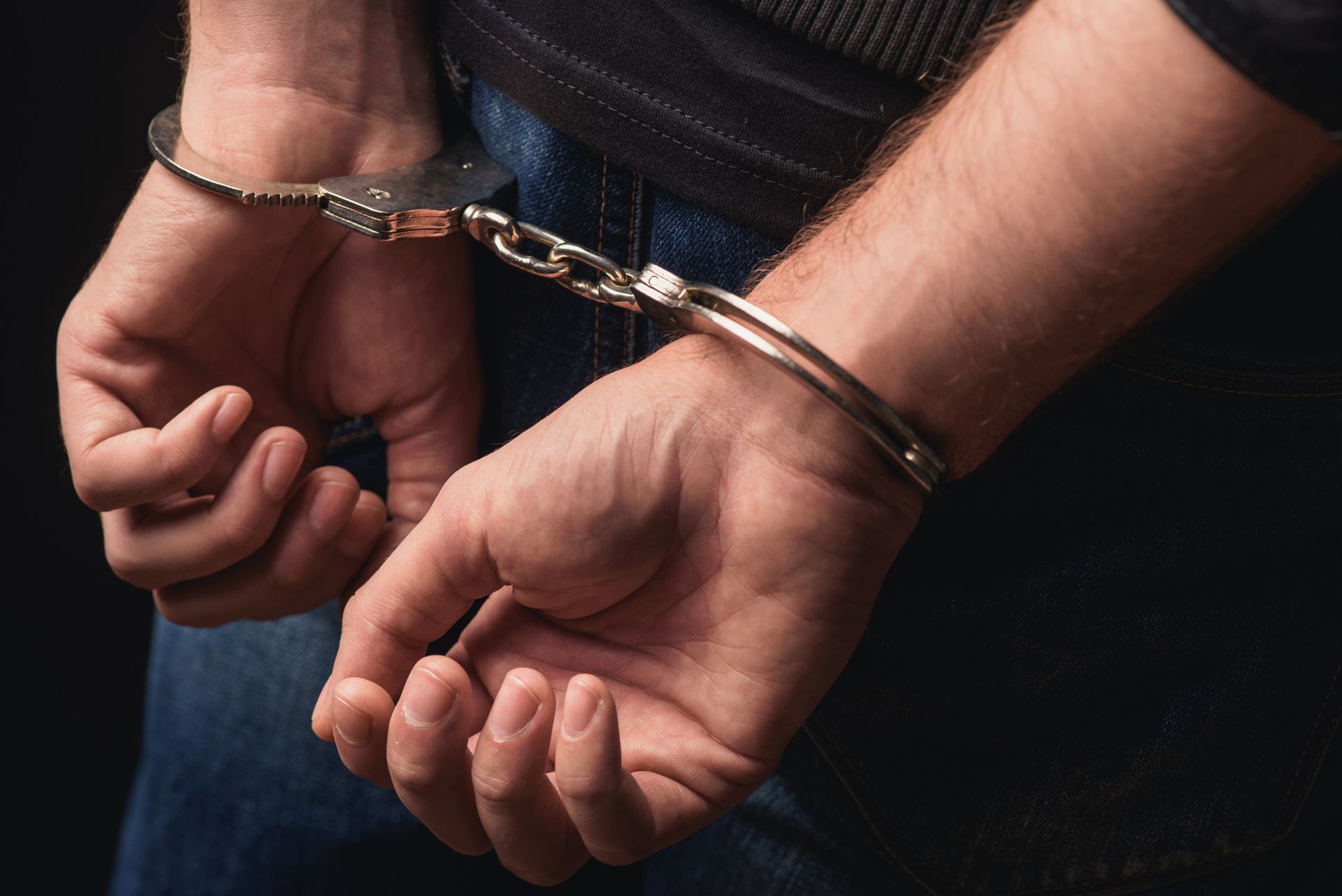 A man with hands on the back with handcuffs.