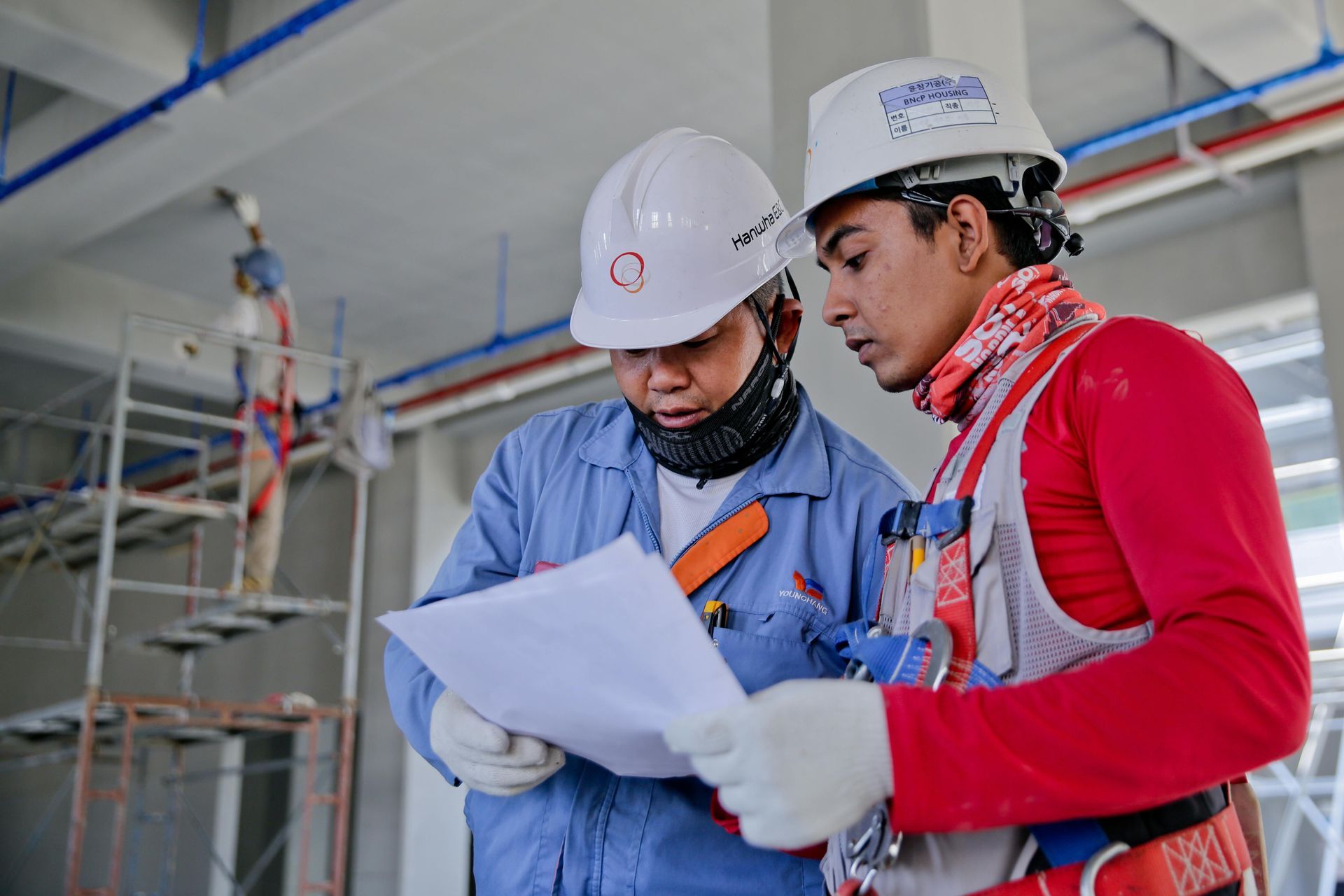 Two construction workers reviewing blueprints on a commercial building site