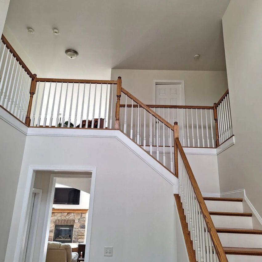 A tall staircase with wood railings and white spindles leading to an upper landing with a closed door.