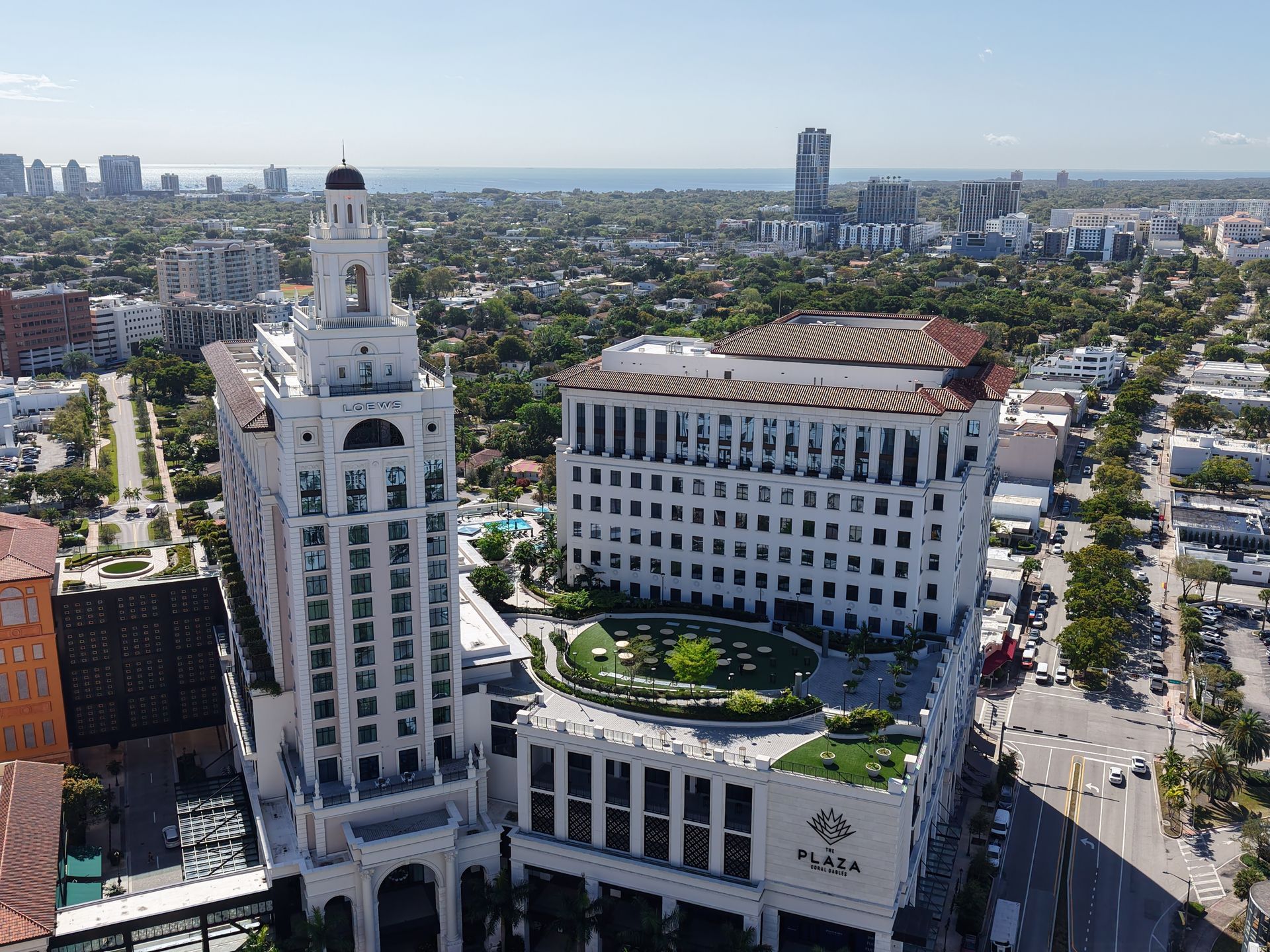 Aerial view of the white, historic-style Plaza Coral Gables building with a central courtyard and clock tower.