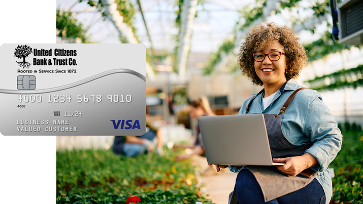 A woman is holding a laptop next to a visa card.