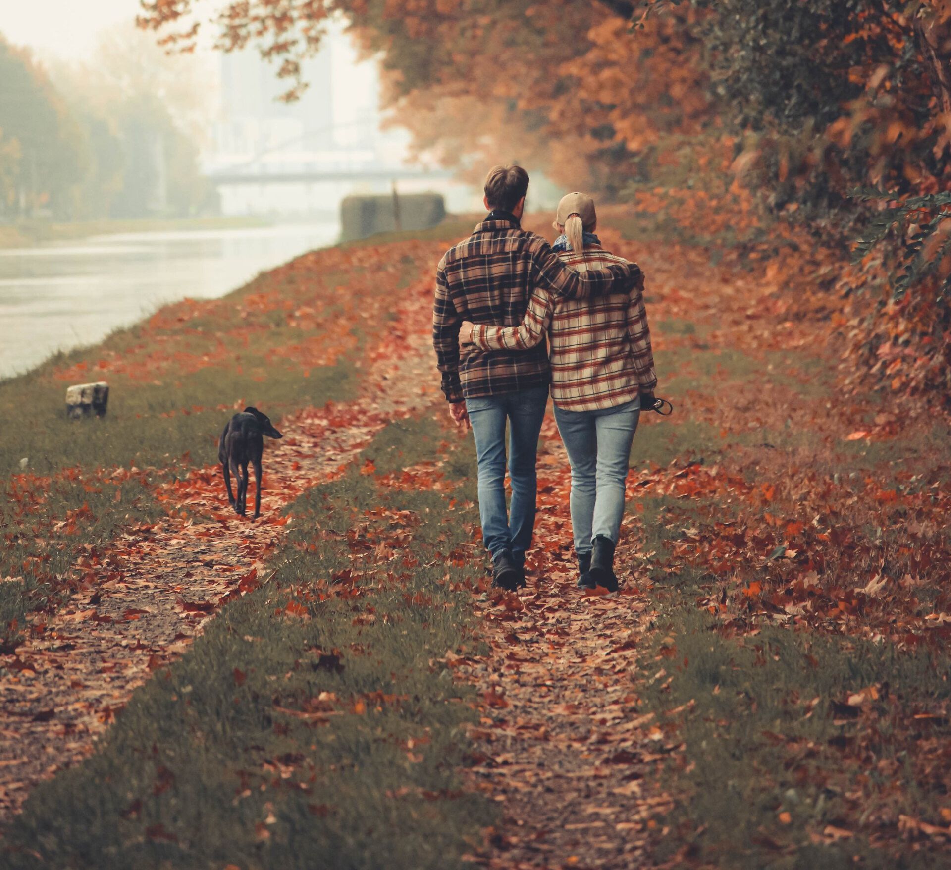 A man and woman are walking down a path with a dog.