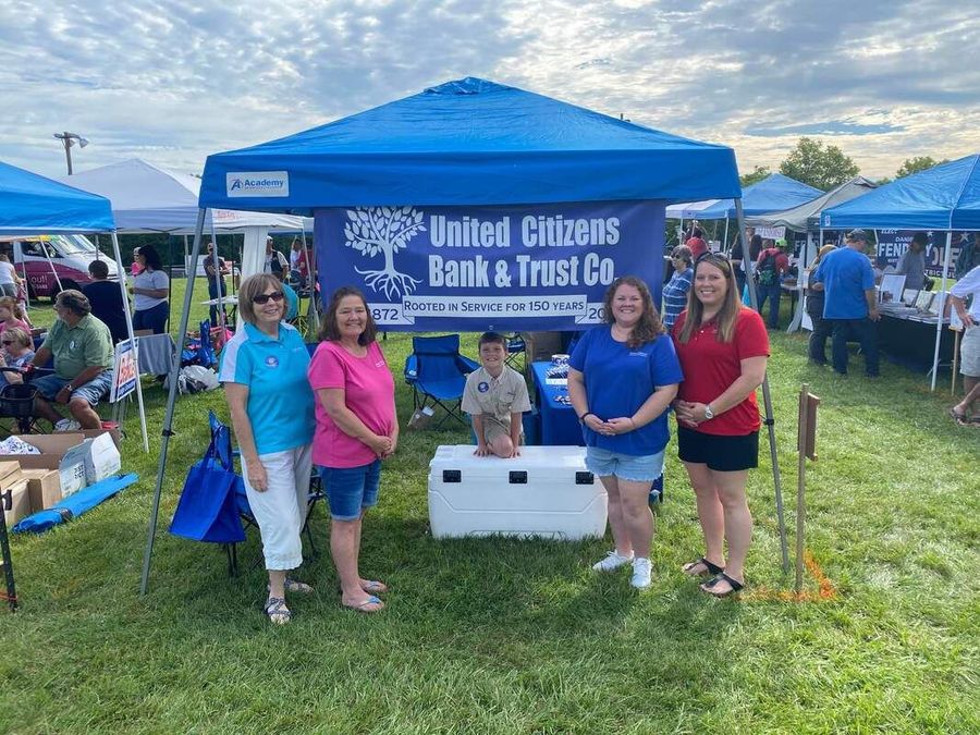 A group of people standing in front of a blue tent.