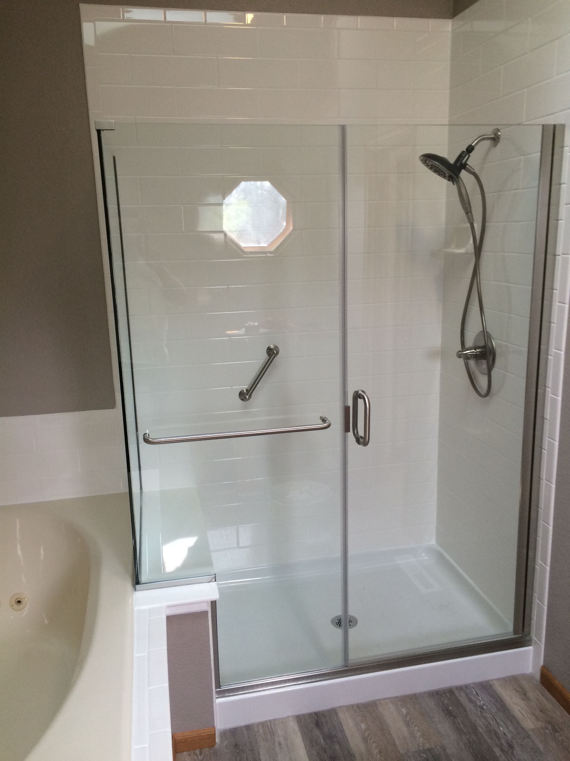 Glass shower enclosure with chrome fixtures in a tiled bathroom.