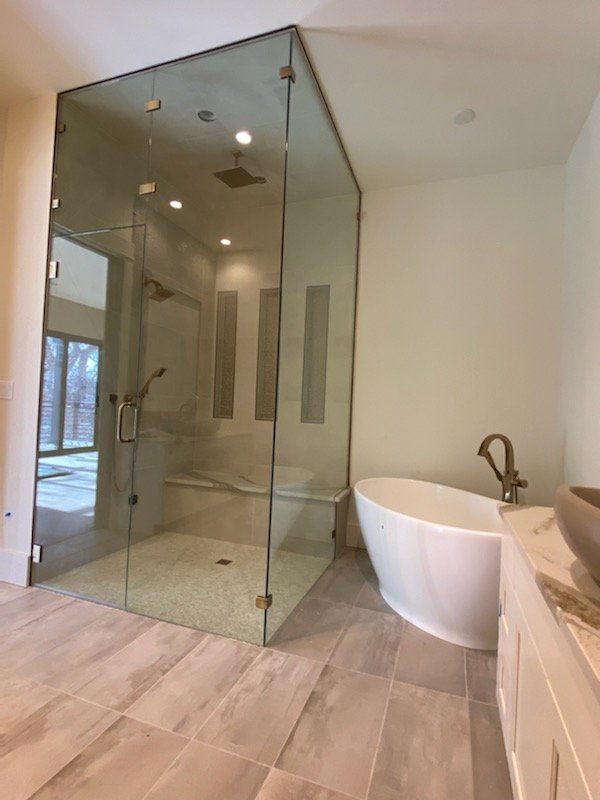 Glass shower enclosure beside a freestanding tub in a bright modern bathroom