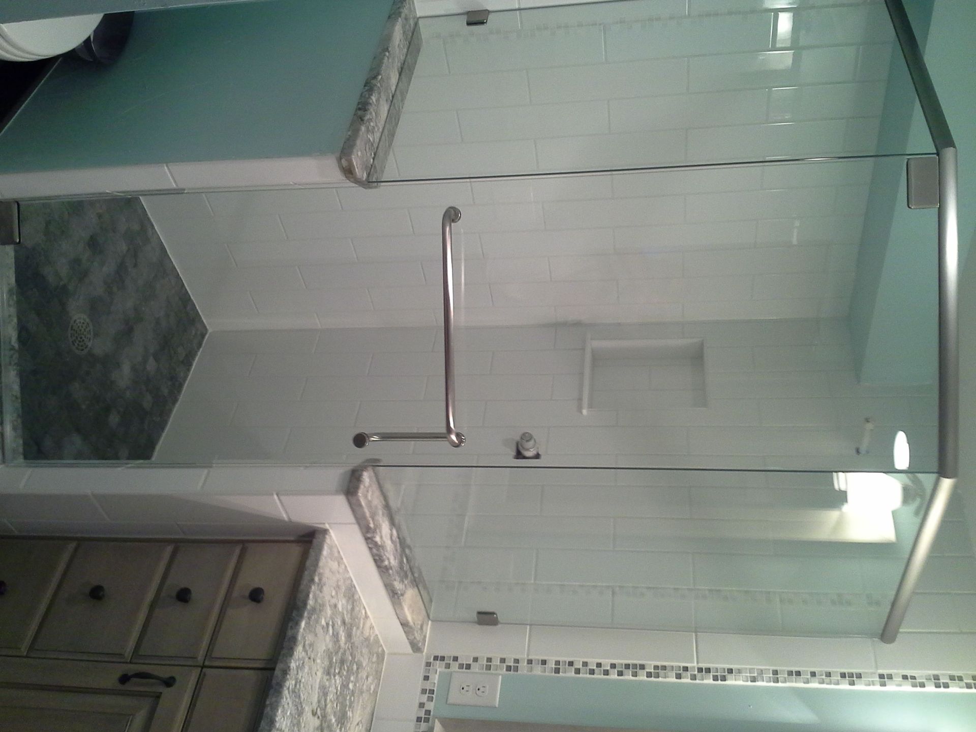 Bathroom with glass shower enclosure, tiled walls, and a small sink cabinet