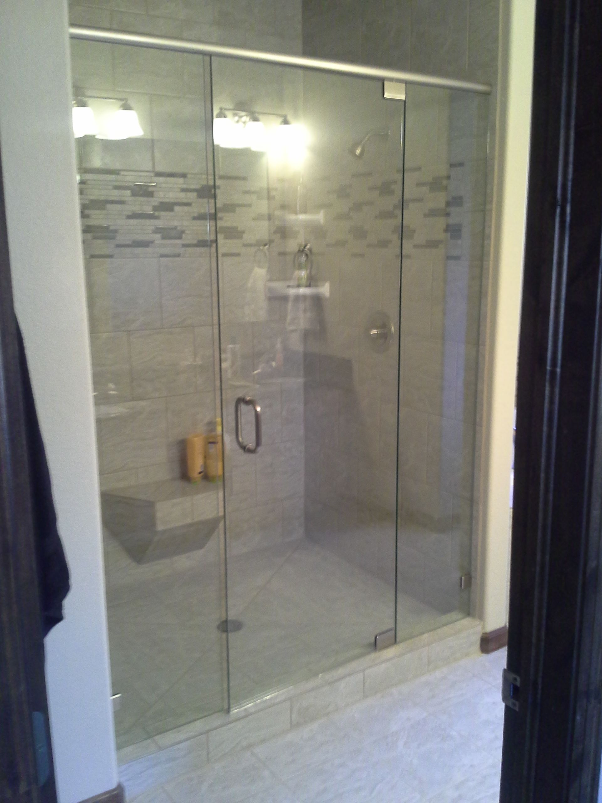 Glass-enclosed tiled shower with frosted sliding doors and built-in bench in a bathroom