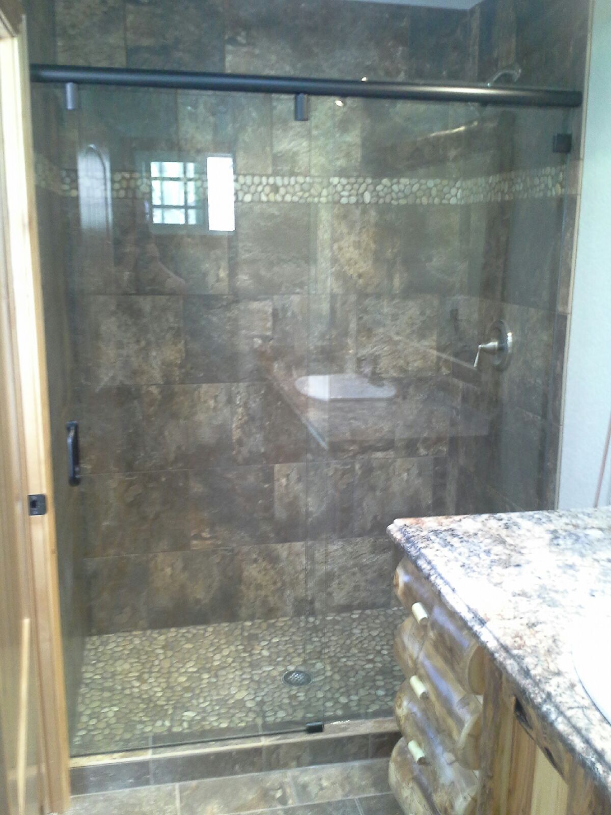 Glass shower with tiled walls and a granite countertop in a bathroom