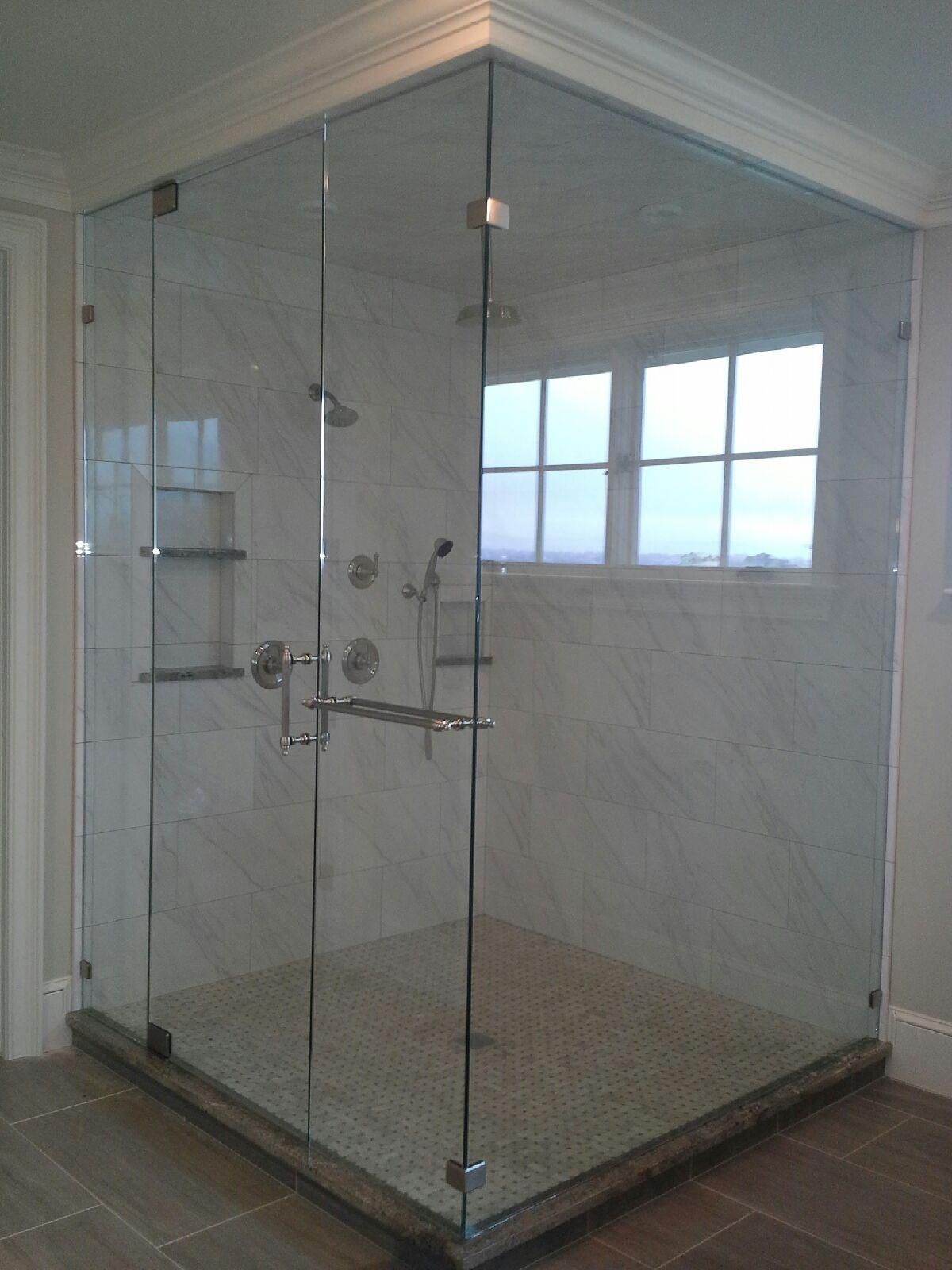 Glass walk-in shower with tiled walls, corner shelves, and chrome fixtures in a bathroom