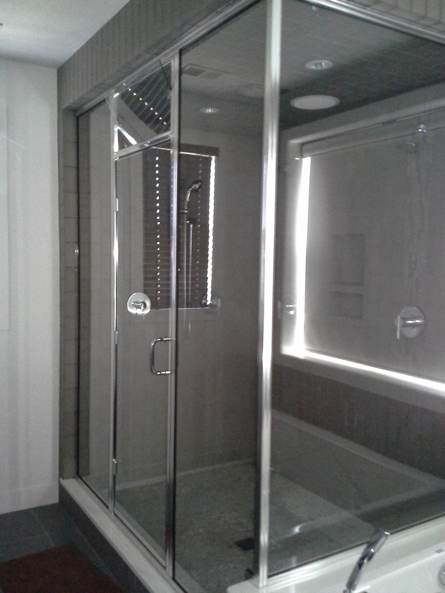 Glass shower enclosure in a bathroom with chrome handles and frosted panels