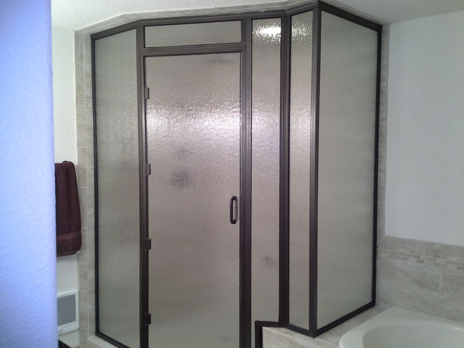 Corner shower enclosure with frosted glass doors in a bathroom