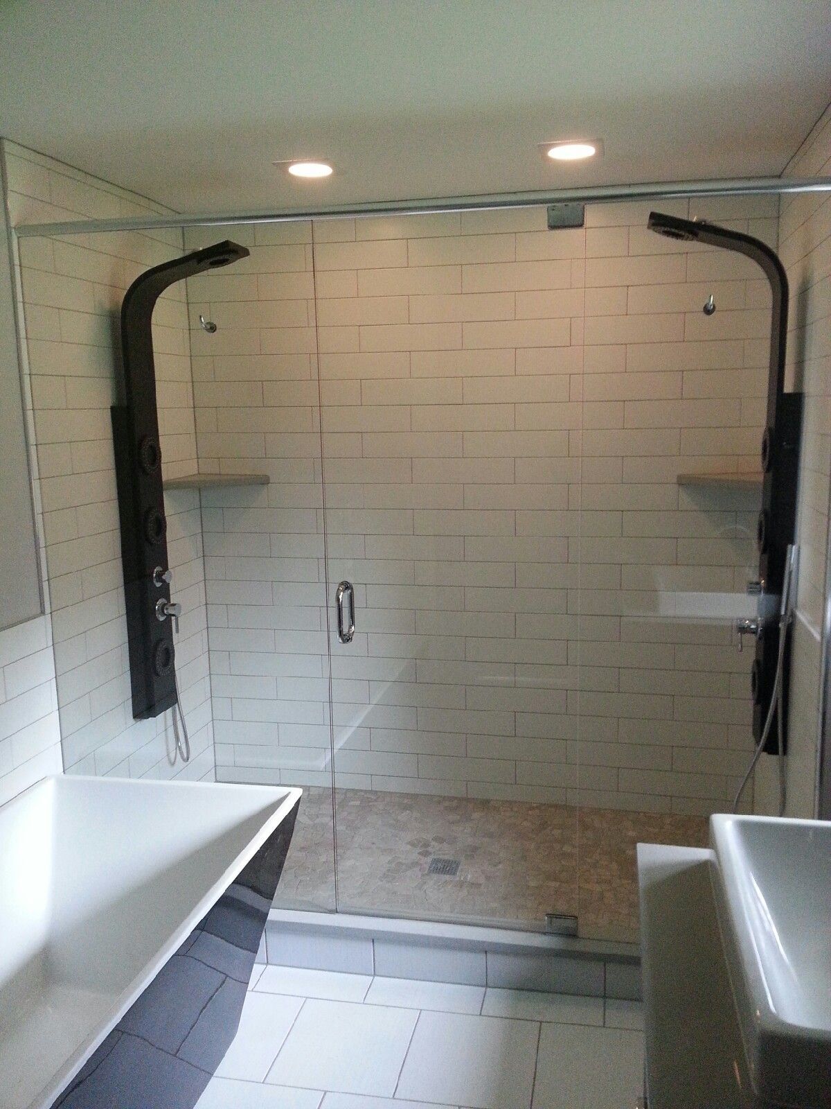Accessible bathroom shower with white tile, grab bars, and a low threshold