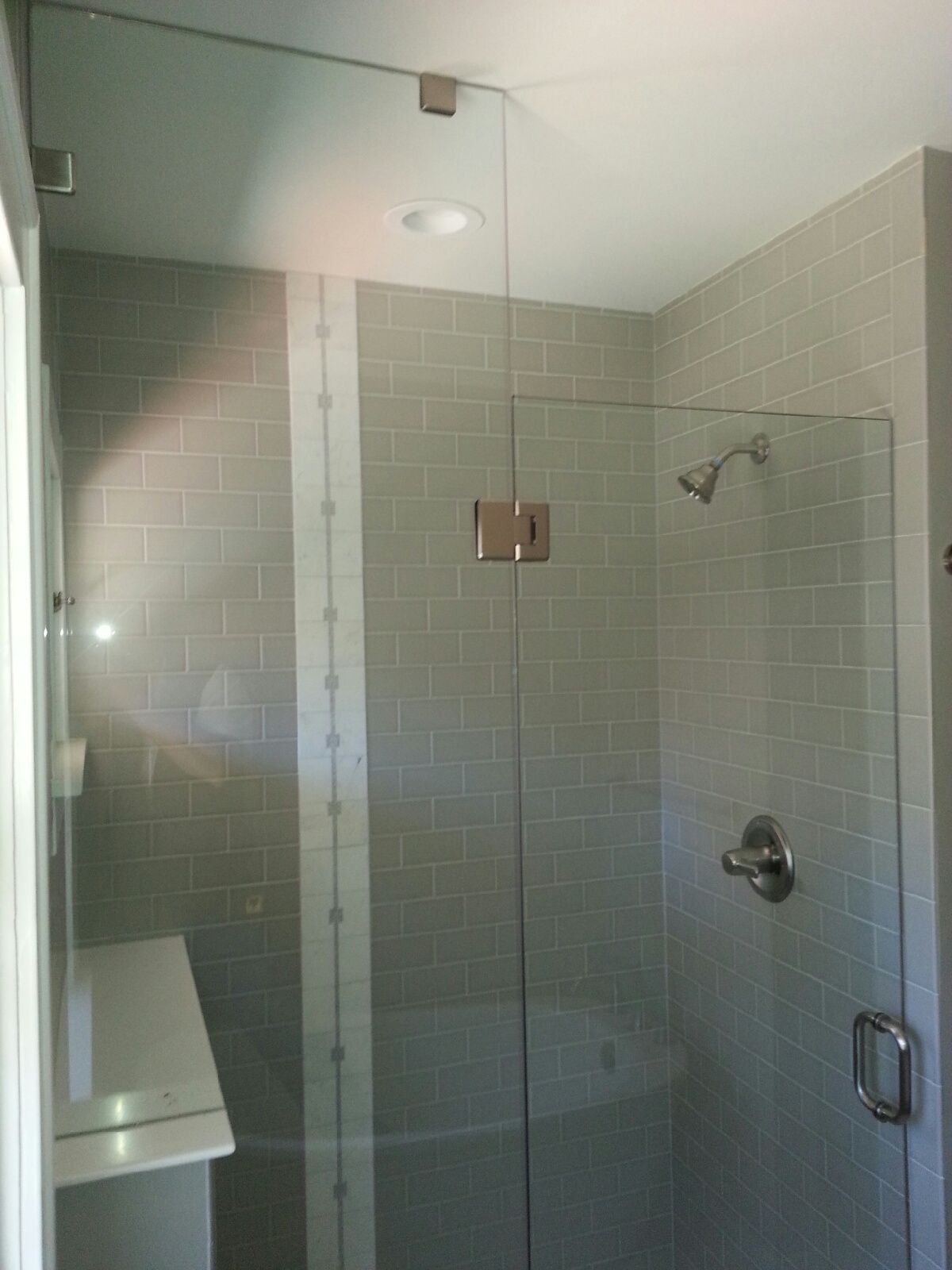 Glass-enclosed tiled shower with chrome fixtures and frosted privacy banding