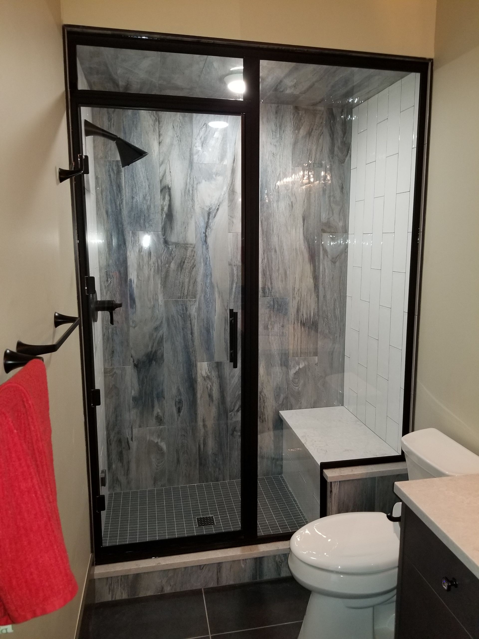 Bathroom with glass shower enclosure, toilet, and vanity counter with mirror.