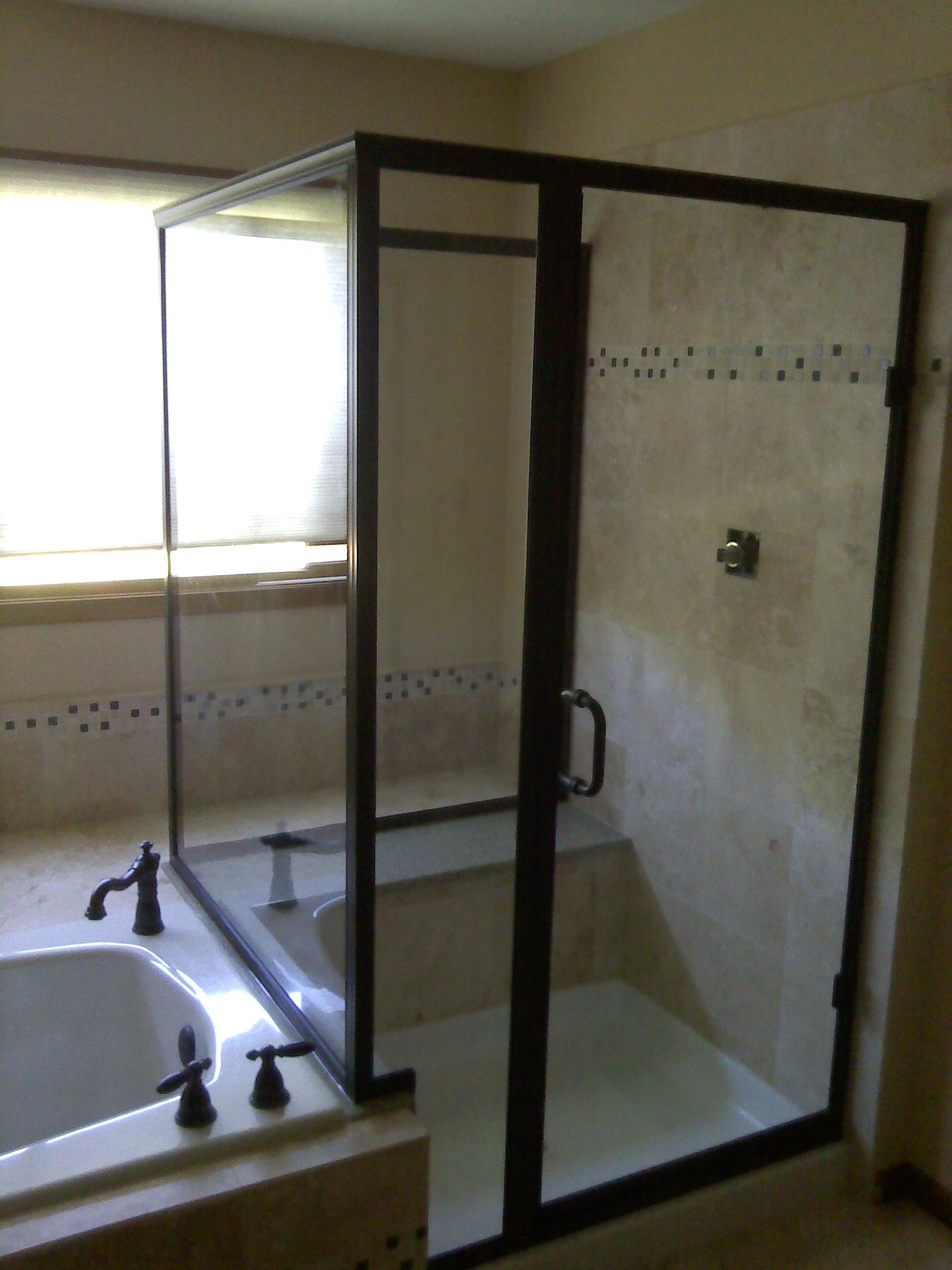 Glass shower enclosure next to a sink in a tiled bathroom