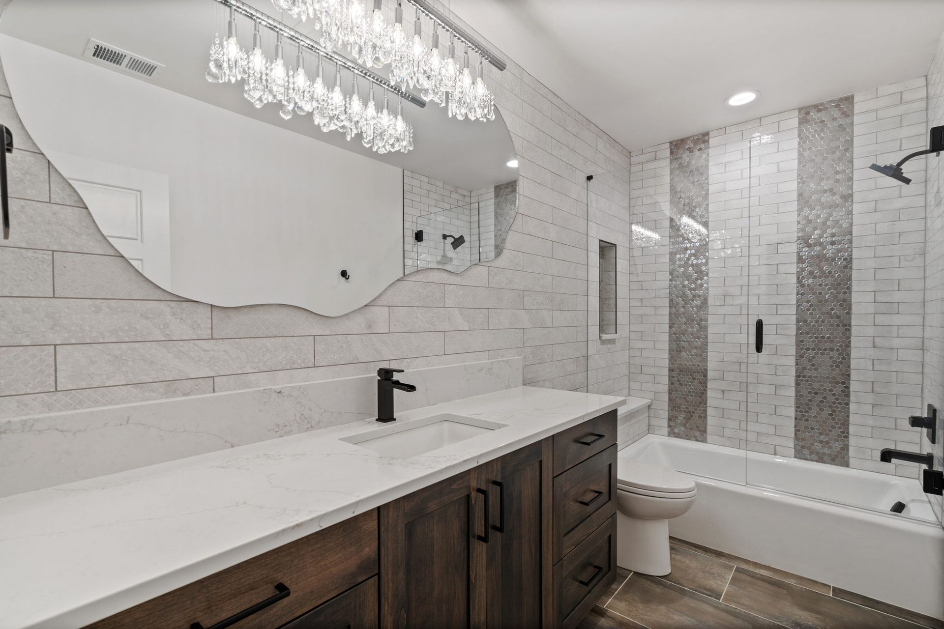 Bright modern bathroom with double vanity, large mirror, and tiled bathtub/shower combo