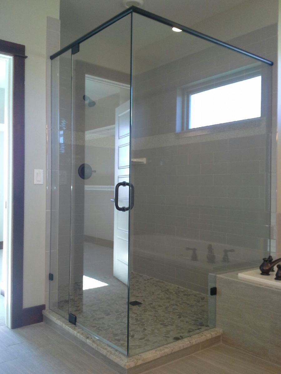Glass shower enclosure with tiled floor and walls in a bathroom