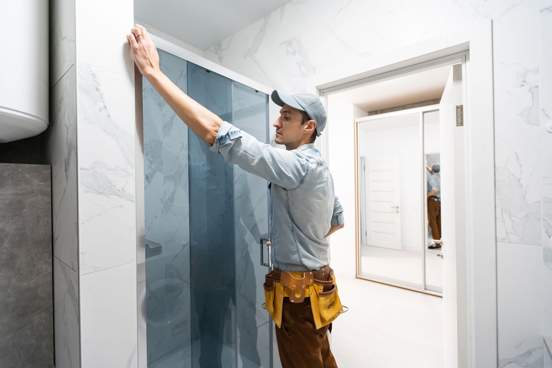 Worker installing wallpaper in a bright hallway, using a tool to smooth the wall.