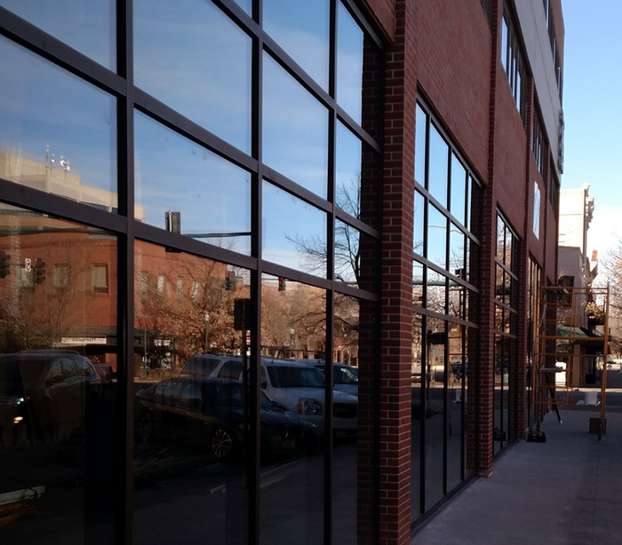 Shoe Store — Fort Collins, CO — Ram Glass Service Brick building with large reflective windows along a sidewalk on a sunny street
