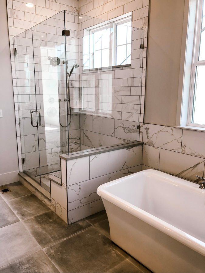 Modern bathroom with glass shower, white subway tile, and a freestanding tub by the window