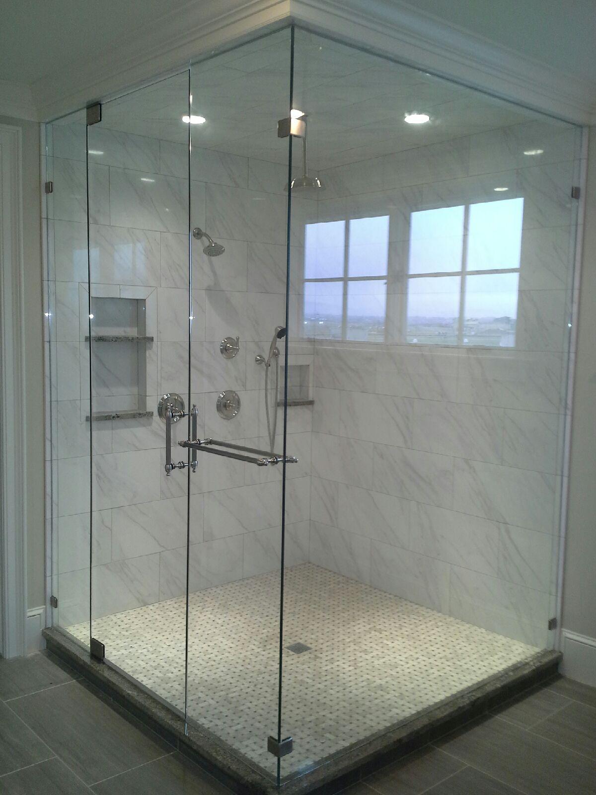 Glass-enclosed walk-in shower with stone tile, pebble floor, and wall shelves